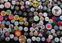 a photo of hundreds of little protest badges pinned to a black scarf.