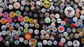a photo of hundreds of little protest badges pinned to a black scarf.