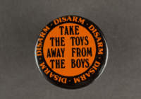 An orange badge with black text that says take the toys away from the boys.