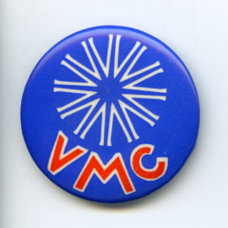 A bright blue badge with a white twelve pronged star on the top half and capital red letters on the bottom half spelling V M C.