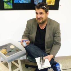 A man sitting on a stool holding a stone