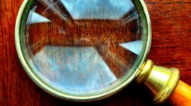 A magnifying glass with a gold metal rim and timber handle