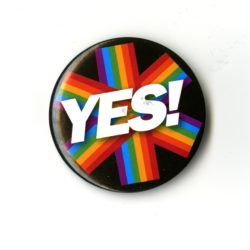 A badge with white text that reads YES. There is a six pringed rainbow star behind the text and a black background.