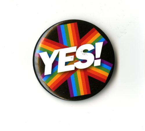 A badge with white text that reads YES. There is a six pringed rainbow star behind the text and a black background.