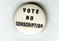 A white badge with black writing. The words read Vote No Conscription.