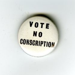 A white badge with black writing. The words read Vote No Conscription.