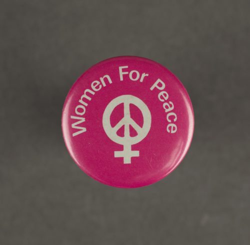 Hot pink badge with a while peace sign displayed in the centre. The words 'women for peach' in displayed arched over the top of the peace sign.