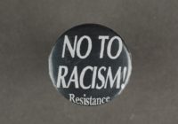 A black badge with white text that says 'no to racism! resistance'