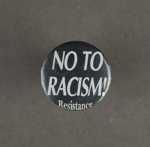 A black badge with white text that says 'no to racism! resistance'