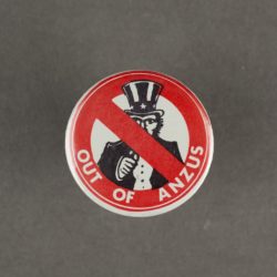 a badge with America's uncle sam in the middle of re circle with a cross through it. Also on the badge is the slogan 'out of ANZUS'